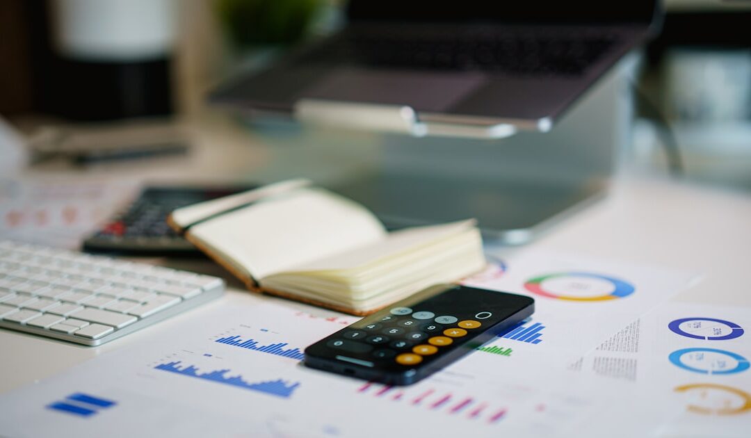 A desk with financial charts and a phone showing figures