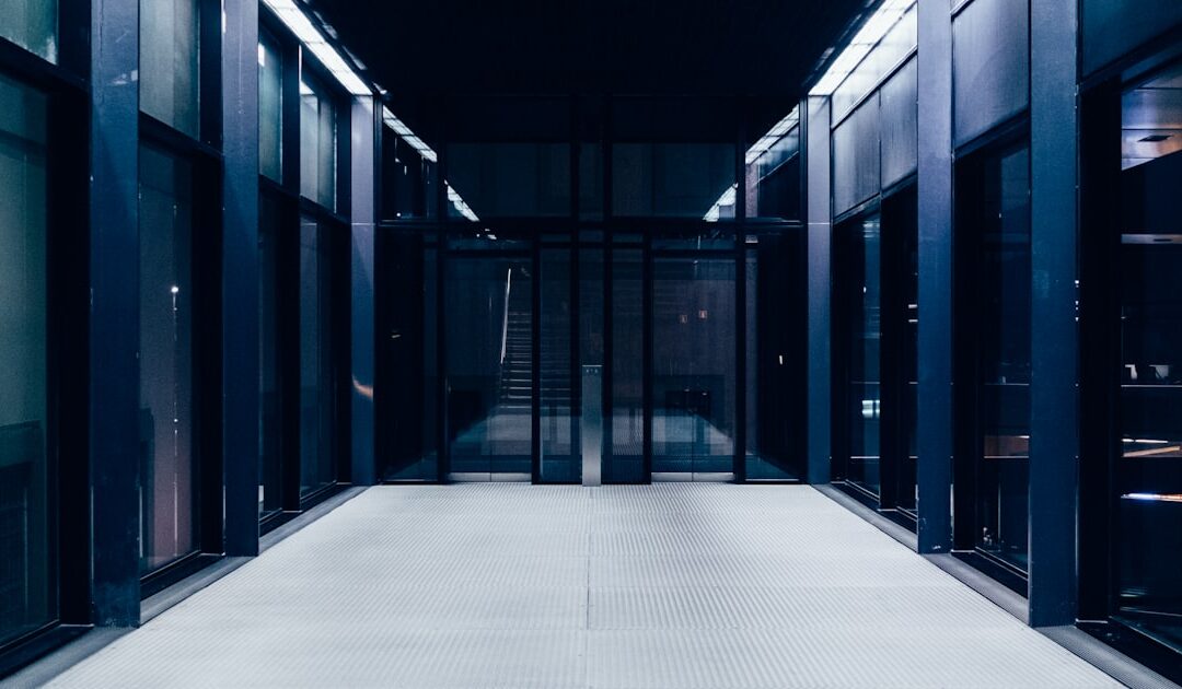 An empty office corridor of glass doors, lit overnight
