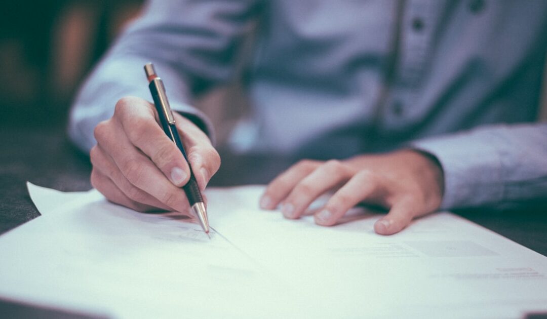 A hand completing a printed form