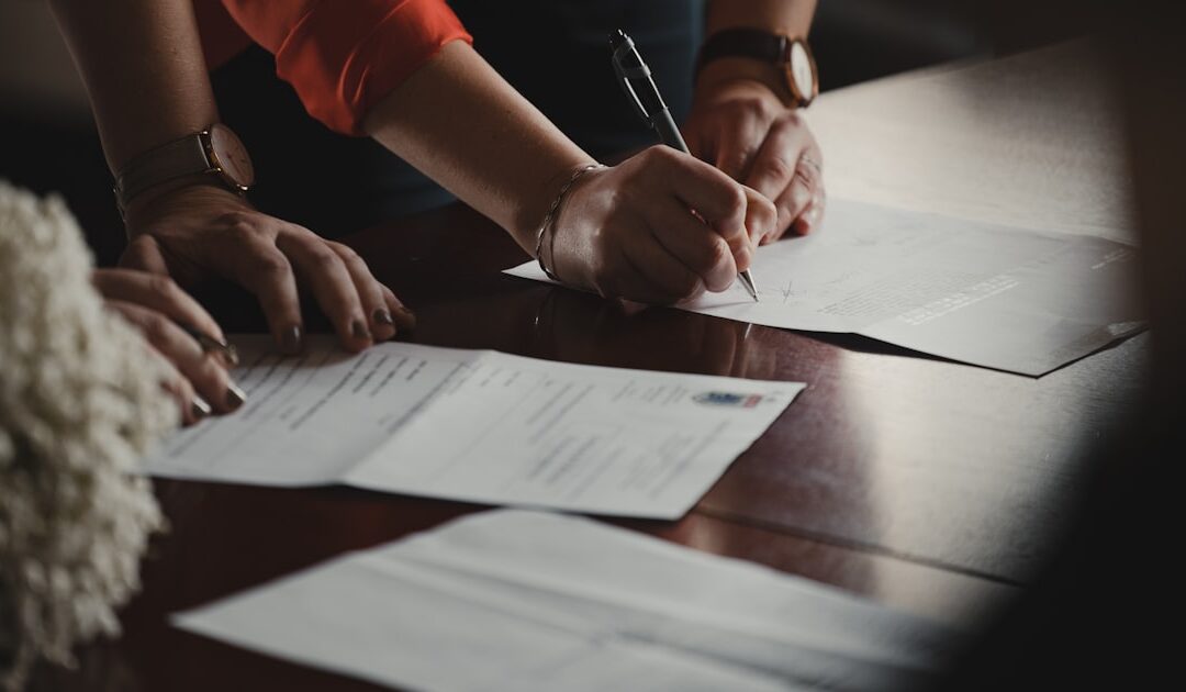 A hand annotating a printed agreement